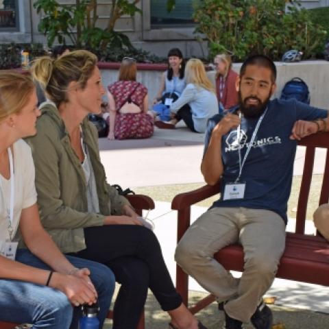 Group of students talking in courtyard sitting on benches