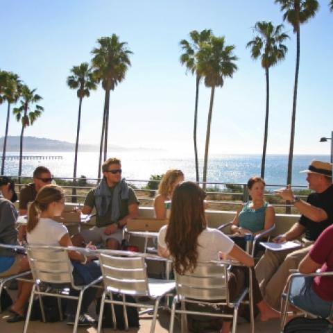 Class group listening to lecture sitting on sunny terrace